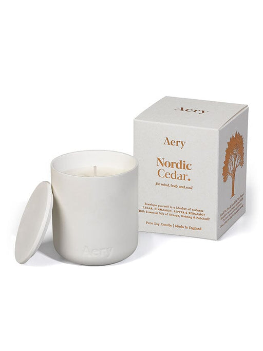 White Nordic Cedar candle by Aery displayed next to  product packing on white background 