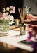 Green Black Oak diffuser by Aery displayed next to vase of white flowers kitchen worktop 