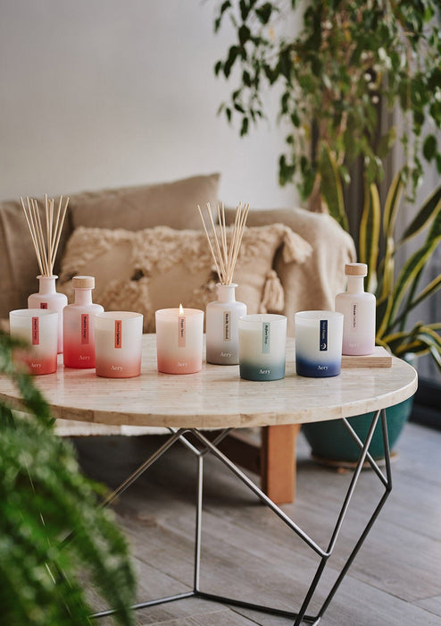 Collection of aromatherapy diffusers and candles by aery displayed on cream circle table in kitchen 