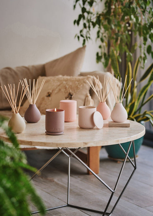 Pink Aztec Tuberose candle by Aery displayed next to fernweh candles and diffusers sat on cream circle table 