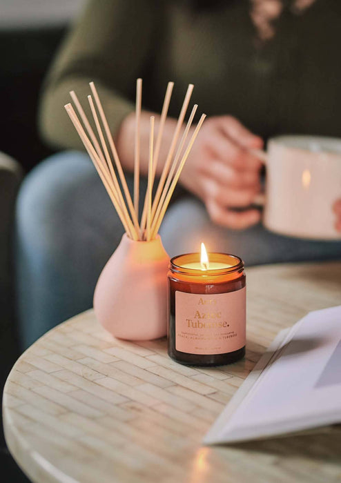 Pink Aztec Tuberose jar candle by aery display next to aztec tuberose diffuser by Aery placed  on cream table