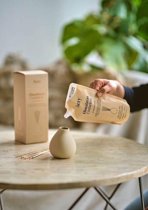 person pouring diffuser refill into pot