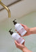 person holding dream catcher body wash and lotion in bathroom setting