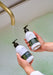 person holding body wash and lotion in bath setting