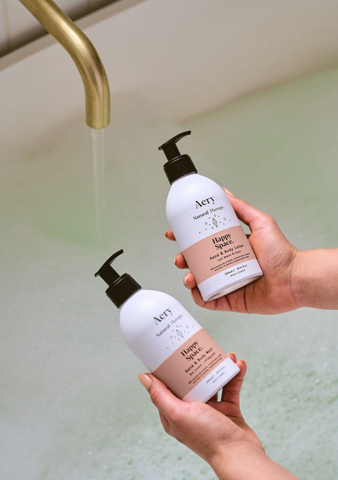 person holding happy space body wash and lotion in bathroom setting