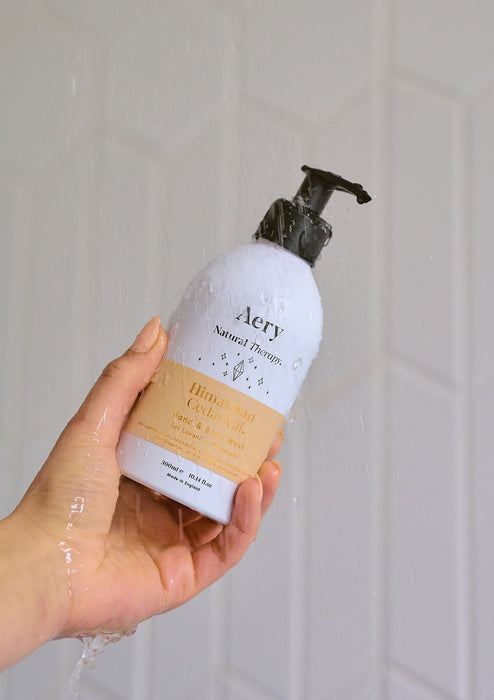 person holding bottle of body wash in shower