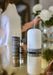 indian sandalwood fragrance oil displayed in home setting next to electric diffuser with person arranging flowers in the background