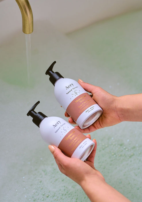 person holding body wash and lotion in bath setting