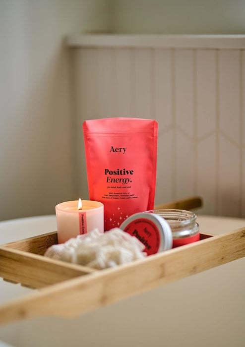 positive energy bath salt refill bag displayed in bathroom setting next to matching bath salts tub and scented candle